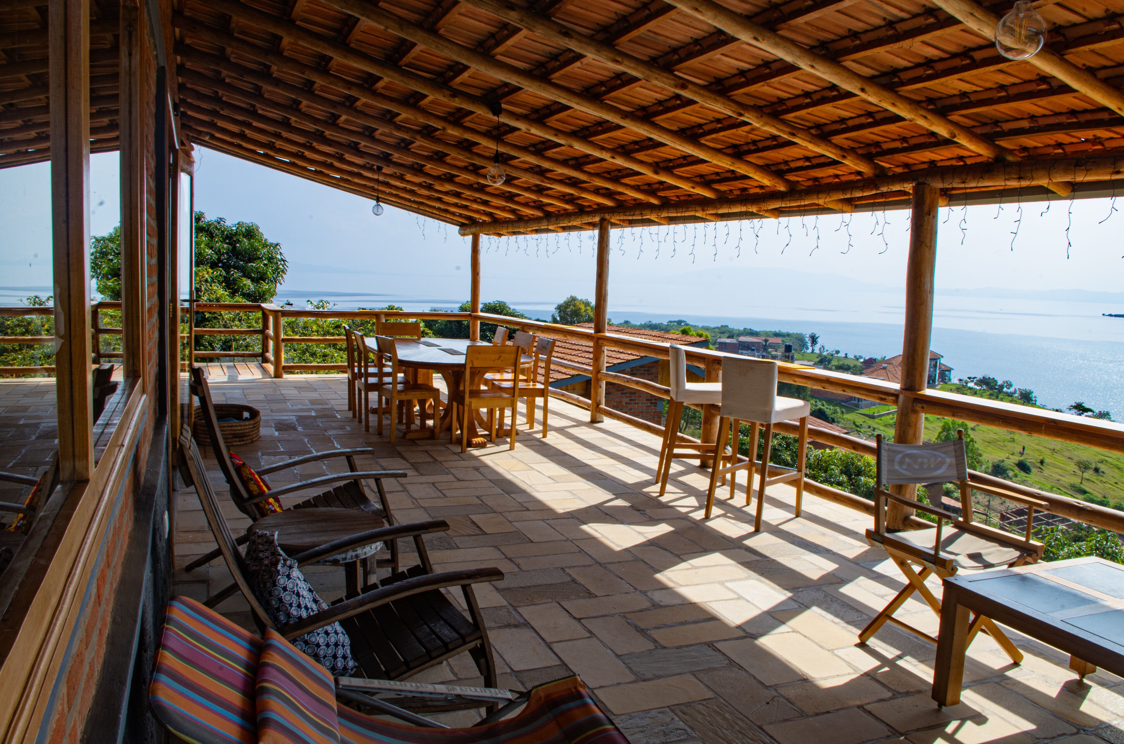 Un espacio de estar al aire libre cubierto con mobiliario de madera y vista al mar.