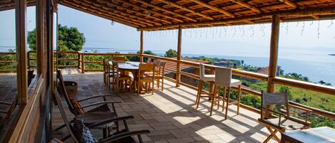 Un espacio de estar al aire libre cubierto con mobiliario de madera y vista al mar.