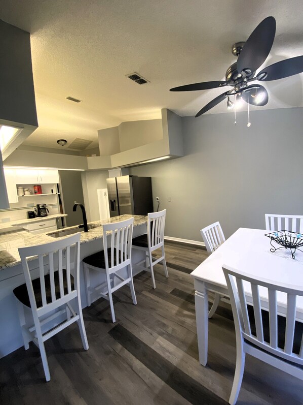 A modern kitchen with white cabinetry, a built-in oven, and a dining area with white chairs and a table. - Cozy 3/2 in the Middle of all the action
Sleeps 7 3 beds 2 bath & air mattress (Lakeland)