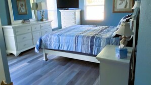 Une chambre à coucher comprenant un lit, une commode, une coiffeuse et un ventilateur de plafond.