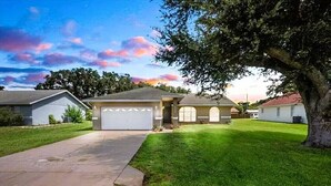 Une maison d’habitation avec un garage, une allée et une pelouse bien entretenue.