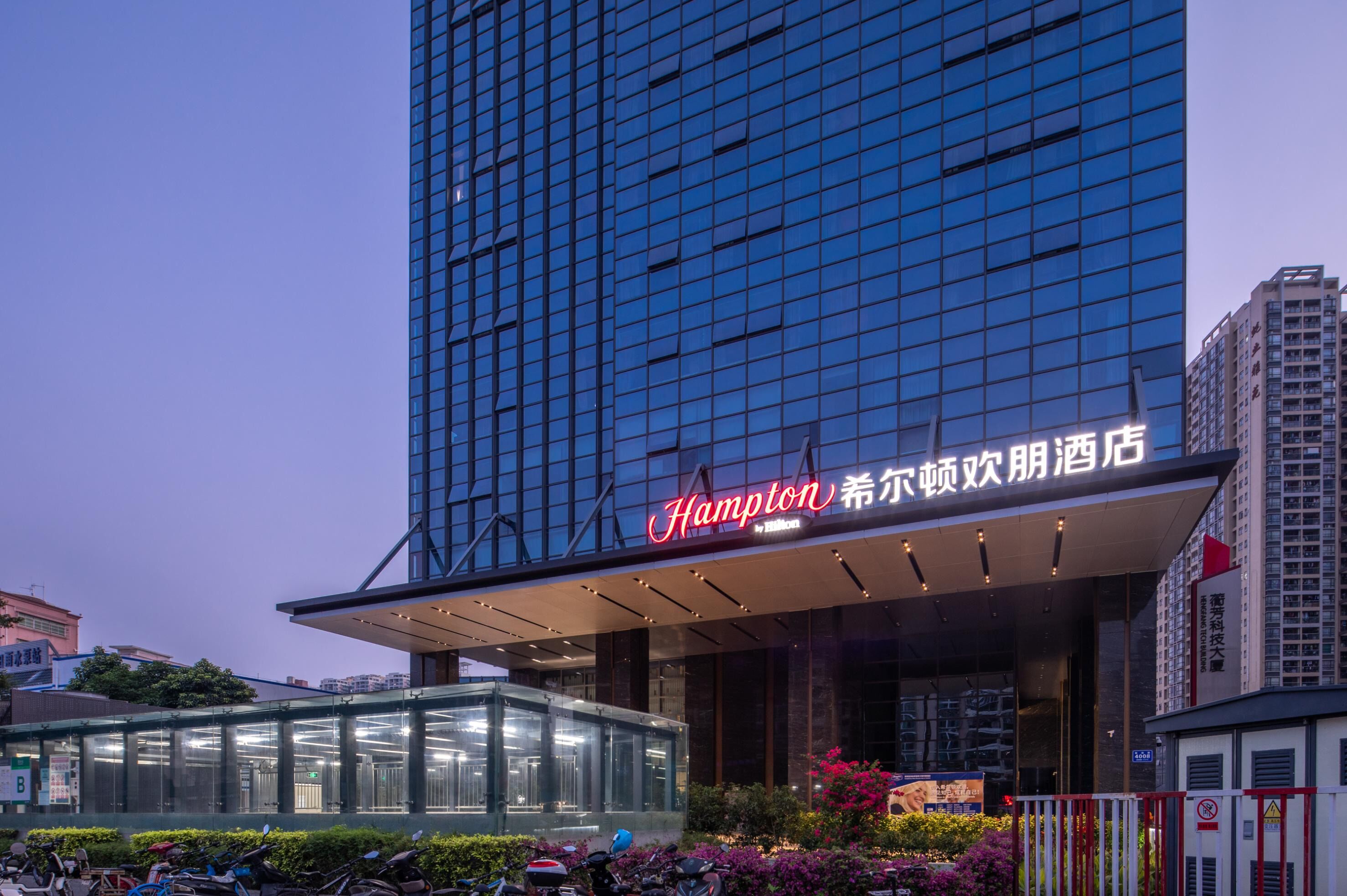 A modern hotel with a glass facade and a prominent sign.