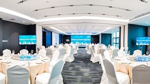 A conference room with round tables, white chairs, and a blue carpet.