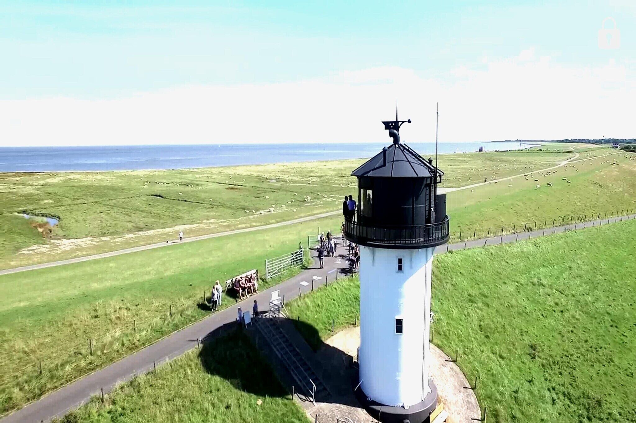 Un phare offrant une vue dégagée sur le paysage environnant, notamment un champ herbeux et un sentier menant à la structure.