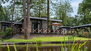 Un bâtiment moderne doté d’un espace extérieur couvert, d’un étang et d’un environnement verdoyant.