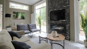 Un salon moderne doté d’une cheminée, de sièges confortables et de grandes fenêtres.