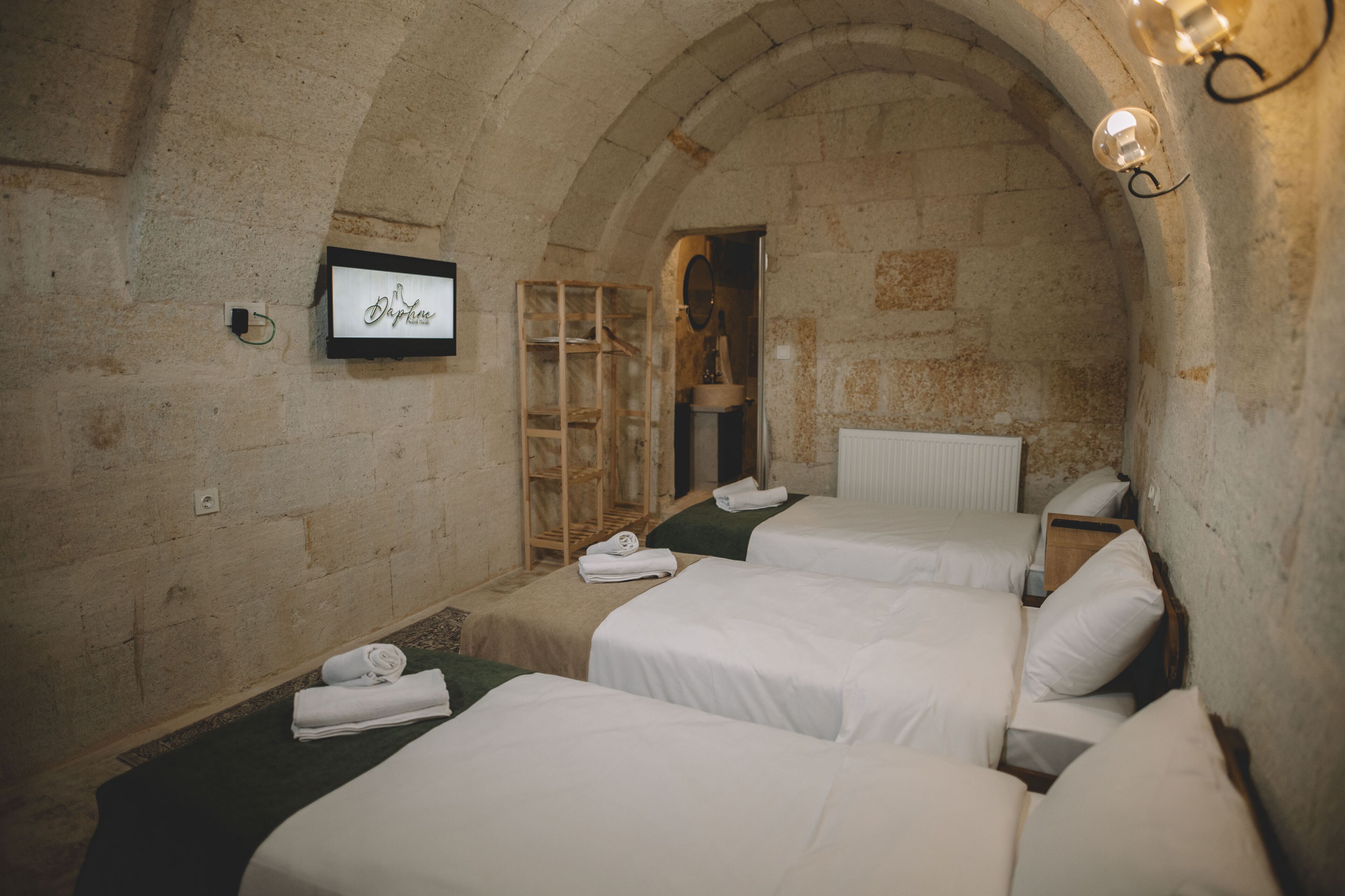 A room with three beds, a wooden ladder, a mirror, and a framed sign on the wall.