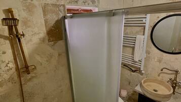 Un bagno con doccia, WC, lavandino e uno specchio.