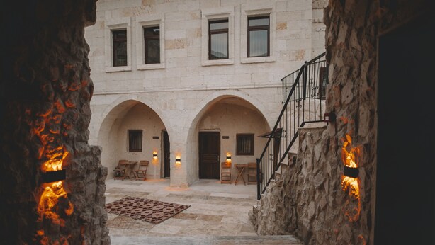 A stone building with arched doorways and a staircase leading to an upper level. - Daphne Cave Cappadocia (Avanos)