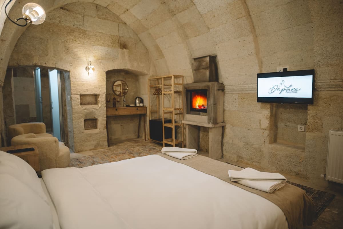 A cozy room with a stone fireplace, a television, and a bed with neatly folded towels.