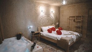 Un dormitorio acogedor con una cama de madera, una bañera con pétalos de rosa y una pared de piedra.