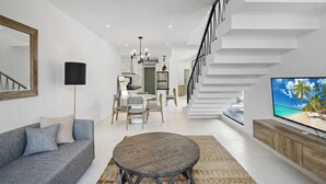 Ein modernes Wohnzimmer mit einer Couch, einem runden Tisch, einem Fernseher und einer Treppe.