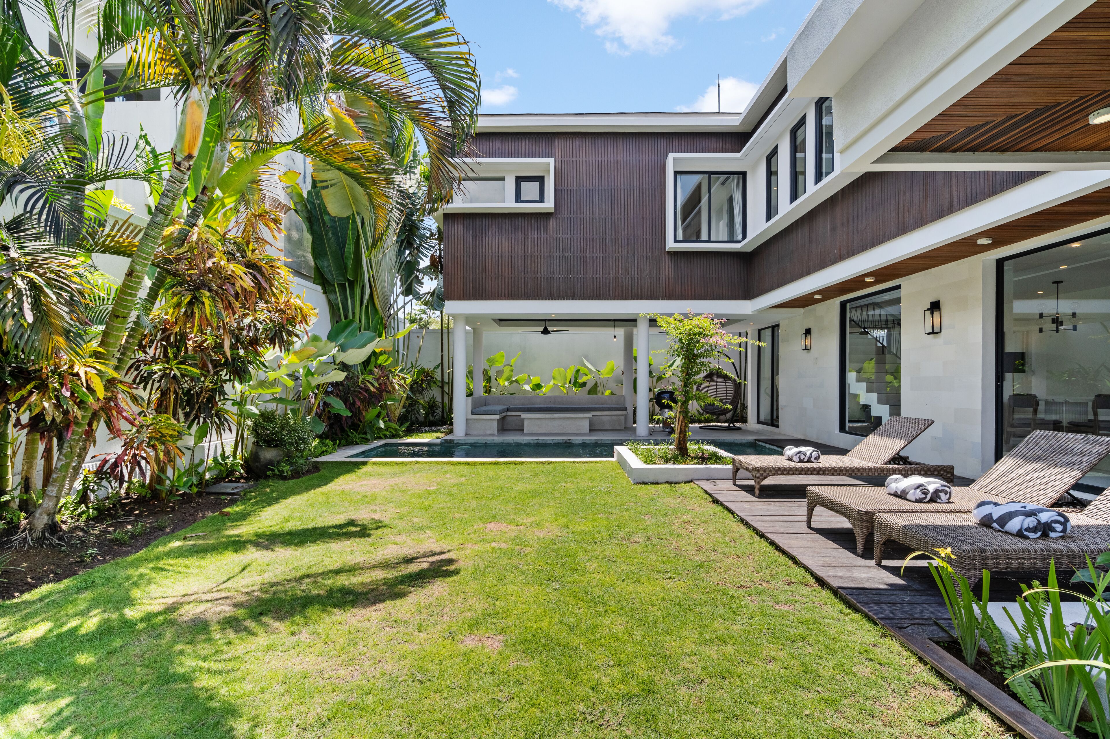 Uma casa moderna com gramado bem cuidado, área de estar externa e piscina.