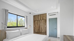 Ein modernes Schlafzimmer mit einem großen Bett, einem Holzschrank, einer blauen Tür und einem Fenster mit Vorhängen.