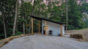 A rustic cabin with a gravel driveway, surrounded by trees. - Luxury Hocking Couples Cabin | Secluded! Hot Tub! (Logan)