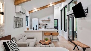 A modern living room with a sofa, a coffee table, and a TV mounted on the wall. - Luxury Hocking Couples Cabin | Secluded! Hot Tub! (Logan)