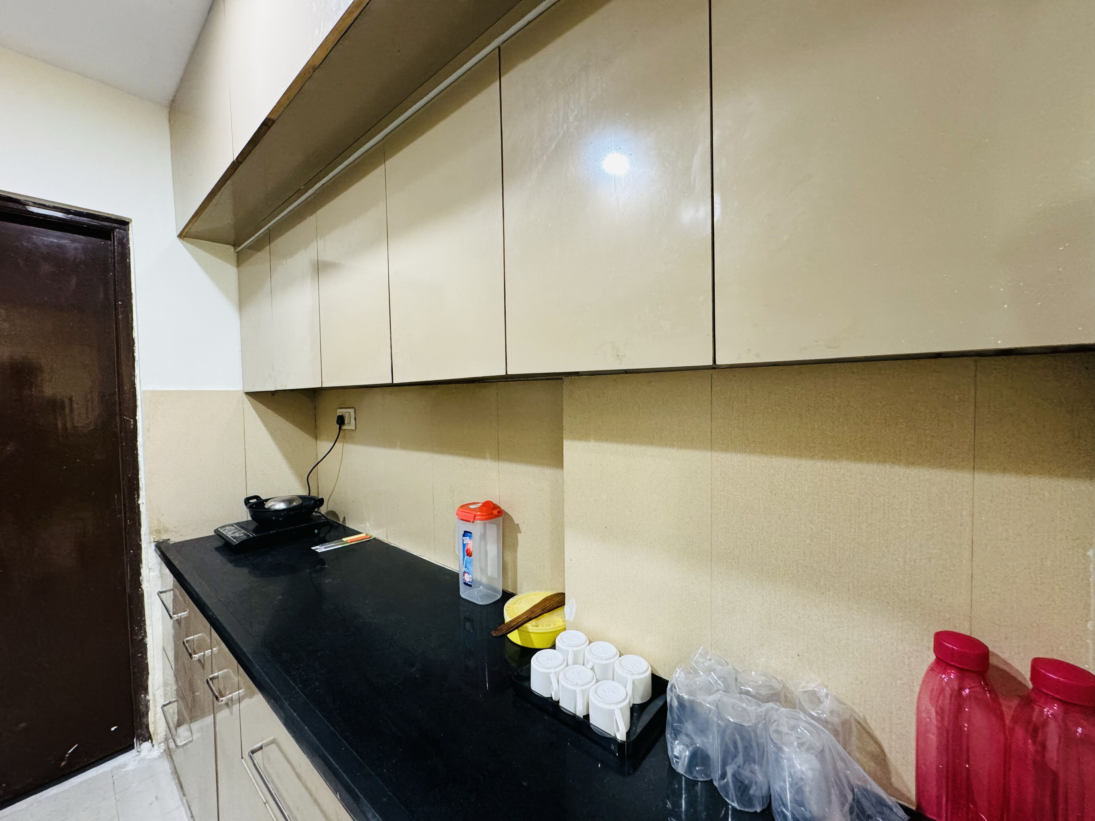 Una cocina con encimera negra, armarios blancos y una puerta.