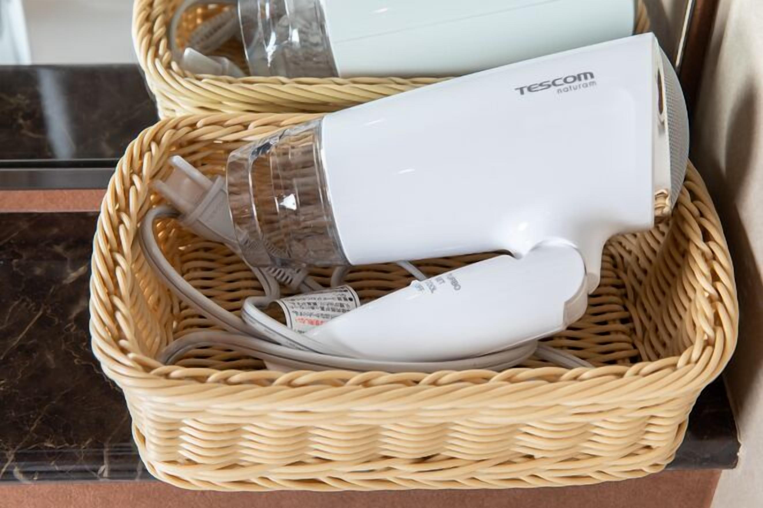 A white hair dryer in a wicker basket.