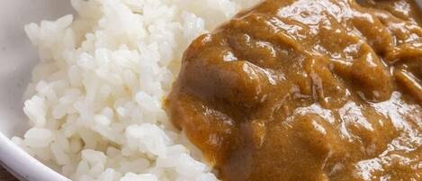 Uma tigela de arroz branco com molho marrom.