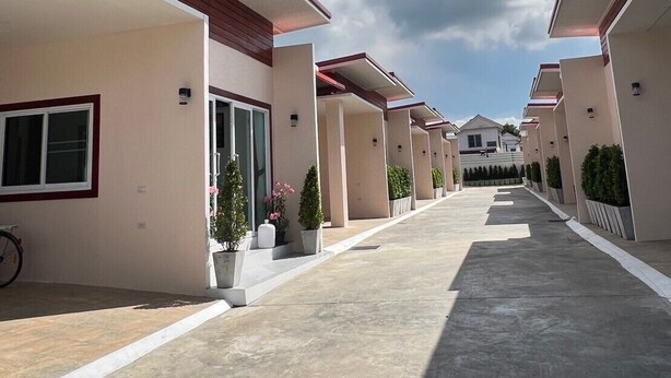A row of modern, single-story buildings with a flat roof and a covered walkway. - PICHAPON  RESORT (Pak Chong)
