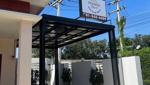 A modern building with a covered entrance, a sign for Pichapon Resort, and visible power lines. - PICHAPON  RESORT (Pak Chong)