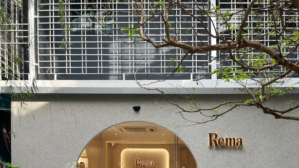 Ein moderner Gebäudeeingang mit einer runden Glastür, einem Empfangstresen und der Aufschrift "Rema" darüber.