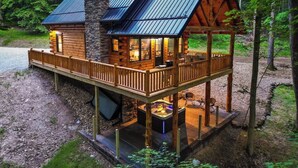 A log cabin with a wooden deck and hot tub.