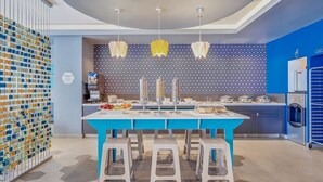 A modern dining area with a blue table and white stools, a patterned wall, and a ceiling with a circular design. - One Morelia Acueducto (Morelia)