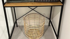 A shelf with folded towels in various colors and a wicker basket below.