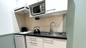 Une cuisine compacte équipée d’un four à micro-ondes, d’une bouilloire, d’un évier et d’un petit réfrigérateur.