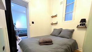 Une chambre à coucher avec un lit, une fenêtre et une porte donnant sur un balcon.