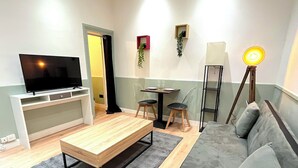 Un salon comprenant un téléviseur, un canapé, une table basse et un coin repas avec des chaises et une table.
