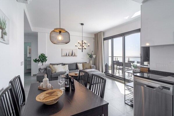 A modern apartment with a dining area, kitchen, and a balcony with a view.