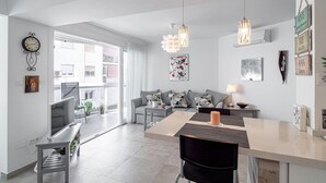A modern living space with a dining area, a sofa set, and artwork on the walls.