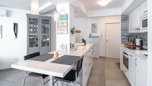 A modern kitchen with white cabinets, a dining area with a table and chairs, and a kitchen island with a candle.