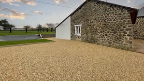 A stone building with a gravel driveway and a fenced area. - Charming granite house with enclosed garden, all inclusive, near Domfront (Saint-Mars-d'Égrenne)