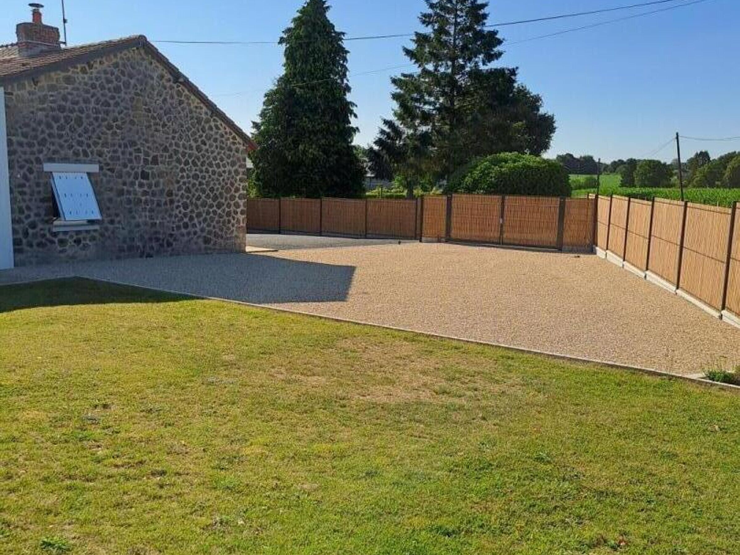 A stone building with a paved driveway and a fenced yard.