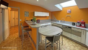 A compact kitchen with a dining area, a small island, and a skylight. - Charming granite house with enclosed garden, all inclusive, near Domfront (Saint-Mars-d'Égrenne)