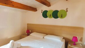 A neatly made bed with white linens and towels, a wooden headboard, and a nightstand with a red lamp. - A-2 Loft Veranda sea view 1st row 1st floor (Fondo Morte)