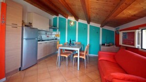 A compact kitchen with a dining area, a red sofa, and a wooden ceiling. - A-2 Loft Veranda sea view 1st row 1st floor (Fondo Morte)