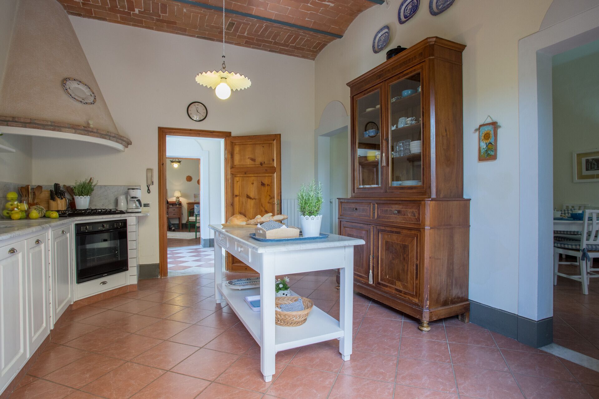Une cuisine avec des meubles blancs, un meuble en bois et un sol carrelé.