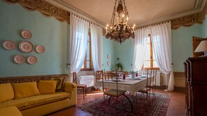 A dining area with a table set for four, a yellow sofa, and a chandelier. - Villa Astro - Homelike Villas (Fabbrica)