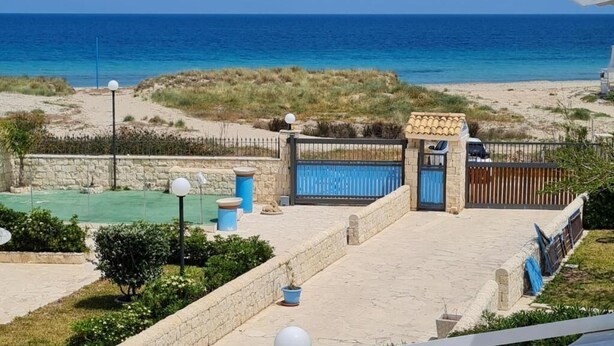 Una propiedad costera con un patio empedrado, un portón y vistas al mar.