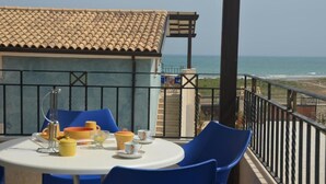 Un balcón con una mesa dispuesta para dos, con vista al mar.
