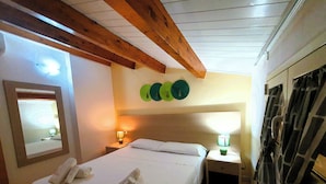 A hotel room with a bed, a nightstand, a mirror, and a wall with circular decorations. - Apartment in attic B2 first row (Fondo Morte)