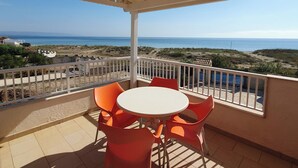 A covered outdoor seating area with a table and chairs, overlooking a beach and ocean. - Apartment in attic B2 first row (Fondo Morte)