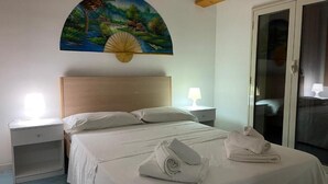 A bedroom with a bed, two bedside tables, a nightstand, a painting, and a sliding glass door. - Apartment D2 sea view first floor (Marzamemi)