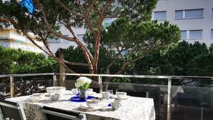 Ein Balkon mit Esstisch, Stühlen und Blick auf Bäume und Gebäude.
