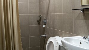 Een badkamer met douche, toilet en wastafel.