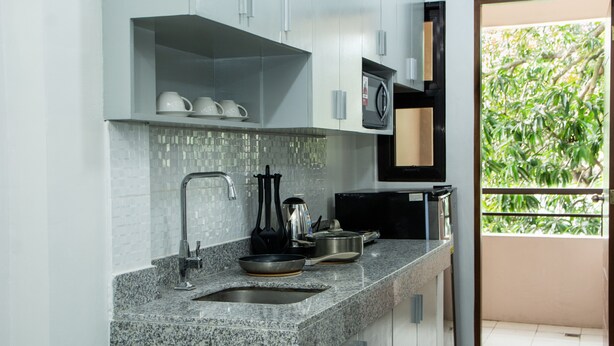 Een moderne keuken met granieten werkbladen, een inbouwspoelbak en een magnetron.